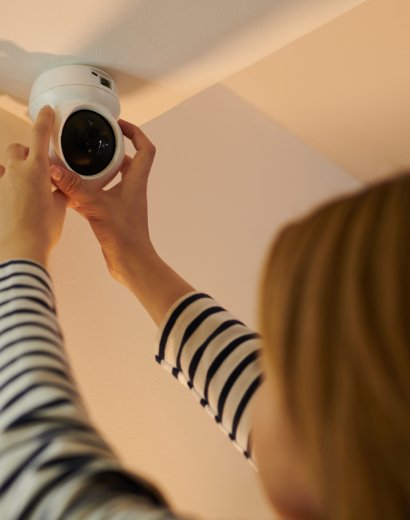 Female technician in London installing a dome security camera, focused on smart home surveillance
